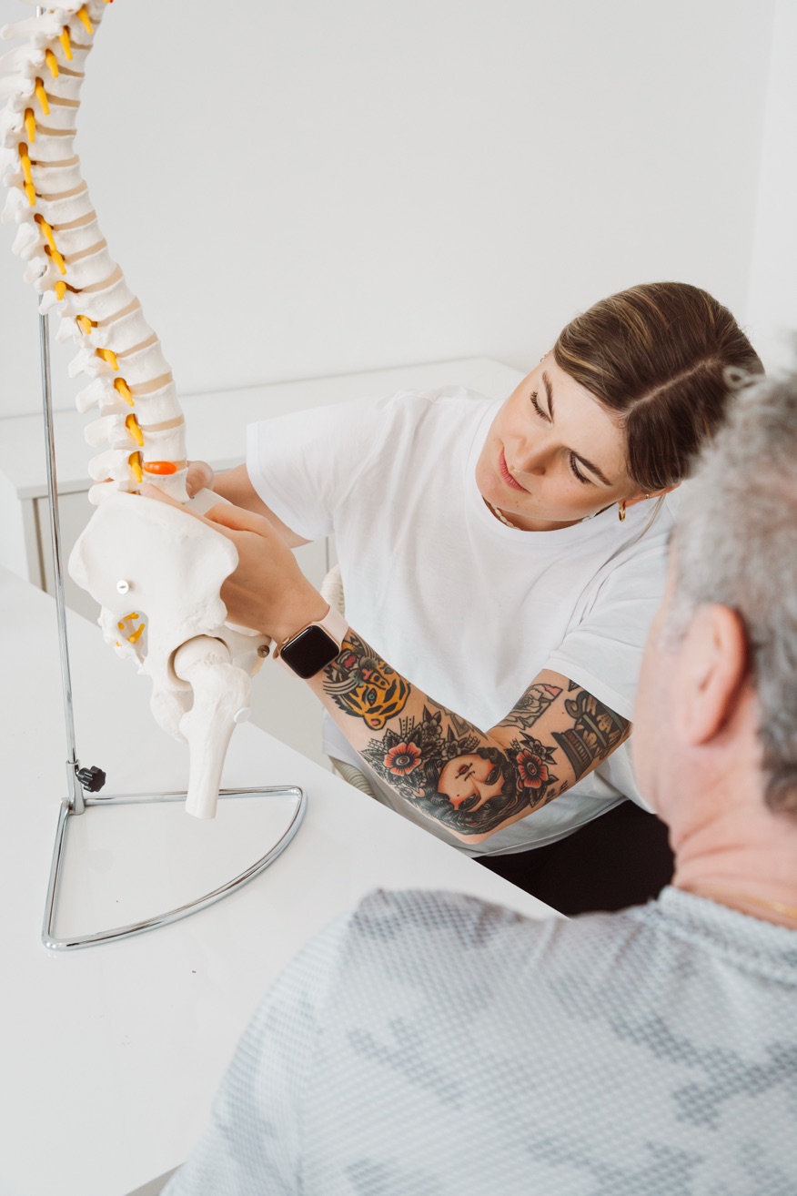 Sophie Leisch erklärt einem Patienten etwas an einem Wirbelsäulenmodell